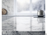 The image shows a kitchen countertop with a white marble countertop. The countertop is in focus, while the background is blur...