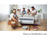 The image shows a group of five people in a living room, gathered around an air conditioning unit. The unit is white and appe...