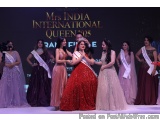 The image shows a group of women on a stage with a banner that reads "Mrs India International Queen 2015". The woman in the c...