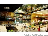 The image is a 3D rendering of a modern shopping mall. The mall has a high ceiling with a skylight above it, allowing natural...