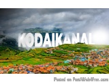 The image is a landscape photograph of a small village in Kodakanal, India. The village is located in a mountainous area with...