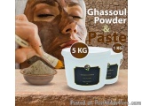 The image shows a woman applying ghassoul powder and paste to her face. The woman is holding a brush in her hand and is apply...