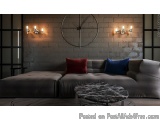 The image shows a modern living room with a gray sofa and a round coffee table in front of it. The sofa is upholstered in a s...