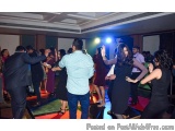 The image shows a group of people dancing on a dance floor in a large room with a high ceiling and a chandelier. The room app...