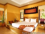 The image shows a modern and luxurious bedroom with a large bed in the center. The bed has a wooden headboard and is covered...