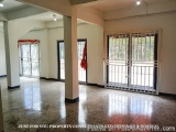 The image shows an empty room with a tiled floor and white walls. The room has two large windows on the right side, one on th...