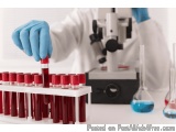 The image shows a laboratory setup with a microscope and several test tubes. The person in the image is wearing a white lab c...