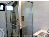 The image shows a modern bathroom with a glass shower enclosure. The shower enclosure is made of glass and has a sliding door...