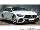 The image is a photograph of a white Mercedes-Benz CLS 63 AMG 4MATIC+ car. The car is parked on a concrete surface with a gra...