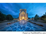 The image is a photograph of a beautiful monument in a park at dusk. The monument is a tall, ornate structure with intricate...