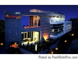 The image is a photograph of a modern hotel building at night. The building is a two-story structure with a curved roof and l...