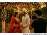 The image shows a newlywed couple standing under a beautiful floral archway. The archway is decorated with pink and white flo...
