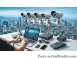 The image shows a desk with a laptop, a calculator, a phone, and a security camera system. The desk is located in front of a...