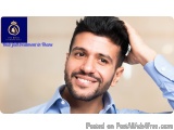 The image is a close-up portrait of a young man with a beard and mustache. He is smiling and looking directly at the camera....