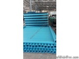 The image shows a stack of blue pipes in a warehouse. The pipes are arranged in a horizontal manner and are stacked on top of...