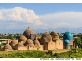 The image shows a beautiful landscape of a mosque with multiple domes and minarets. The mosque is located in a hilly area wit...