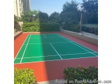 The image shows an outdoor tennis court in a residential area. The court is made of red and green tiles, with white lines mar...