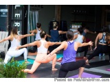 The image shows a group of women in a yoga class. They are all wearing workout clothes and are on yoga mats on the floor. The...