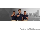 The image shows three young people, two girls and a boy, standing in front of a cityscape. They are all wearing navy blue pol...
