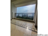 The image shows an empty balcony with a view of the city. The balcony has a black metal railing and a white tiled floor. The...