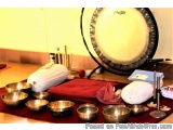 The image shows a set of Tibetan singing bowls arranged on a red mat on a wooden floor. There are six bowls in total, each wi...