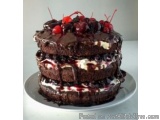 The image is of a three-tiered chocolate cake on a white plate. The cake is made up of three layers, with the top layer being...