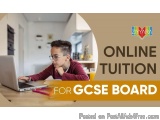 The image shows a young boy sitting at a desk with a laptop in front of him. He is wearing a maroon sweater and glasses and a...