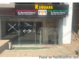 The image shows the entrance of a clinic named R Square. The clinic is located in a building with a glass door and a signboar...