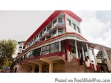 The image shows a modern building with a unique design. The building has a red and white color scheme with a triangular shape...