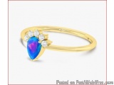 The image is of a gold ring with a large, oval-shaped opal in the center. The opal is a deep blue color and is surrounded by...