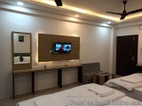 The image shows a modern and spacious bedroom with two single beds. The beds are neatly made with white linens and have white...