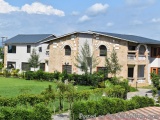 The image shows a two-story building with a modern design. The building has a flat roof and is made of light-colored stone. T...