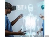 The image shows two people wearing blue scrubs and virtual reality (VR) headsets. They are standing in front of a large scree...