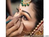 The image is a close-up of a woman's face, likely a bride getting ready for her Hindu wedding. She is wearing a traditional I...