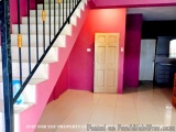 The image shows a staircase with a black metal railing on the left side and a white tiled floor. The walls are painted in a b...