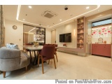 The image shows a modern and luxurious living room and dining area. The room has a high ceiling with recessed lighting and a...
