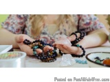 The image shows a person's hands holding a stack of colorful beaded bracelets. The bracelets are made up of small, round bead...