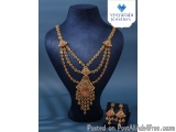 The image shows a necklace and earring set displayed on a black mannequin. The necklace is made of gold and has a pendant in...
