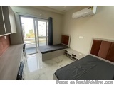 The image shows a modern and spacious bedroom with a large window on the left side. The room has a white tiled floor and a wo...