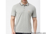 The image shows a man wearing a light grey polo shirt with a collar and short sleeves. The shirt has a small orange logo on t...