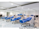 The image shows a modern hospital room with multiple blue medical beds. The beds are arranged in a row and are equipped with...