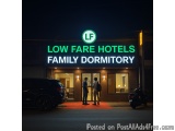 The image shows the entrance of a hotel named "Low Fare Hotels Family Dormitory". The hotel is located on a street at night,...