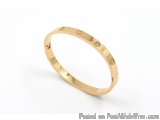 The image is of a gold bangle bracelet. The bracelet is made of a thin, polished metal and has a smooth, polished finish. It...