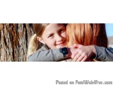 The image shows a young girl with blonde hair, wearing a gray sweater, hugging her mother's shoulder. The girl is smiling and...