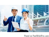 The image shows a man and a woman wearing blue hard hats and holding a laptop. They are standing on a rooftop with a city sky...