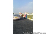 The image shows a group of four people standing on the side of a road. The road appears to be empty, with no cars or people v...