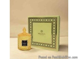 The image shows a small glass jar with a gold lid and a green box with a black and white patterned design. The jar is placed...