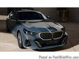The image is a photograph of a blue BMW 5 Series sedan car. The car is parked on a concrete surface with a concrete wall in t...
