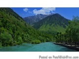 The image shows a beautiful landscape of a mountainous area with a river flowing through it. The river is surrounded by lush...