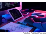 The image shows a person working on a computer at a desk. The desk is cluttered with various items such as a keyboard, a tabl...